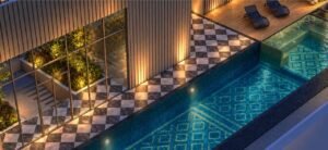 Luxe Pool and Jacuzzi at MABA Suitez featuring blue patterned pool tiles, a checkerboard deck, glass railings and sun loungers.