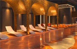 The Sunlit Pool, a Tower B sky facility at MABA Suitez, with white loungers beneath perforated golden cabana arches